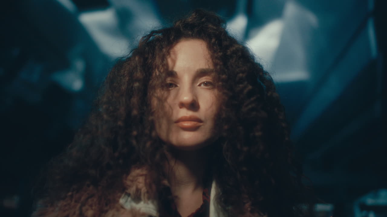 Portrait of Young Attractive Woman with Curly Hair in Dark Underpass
