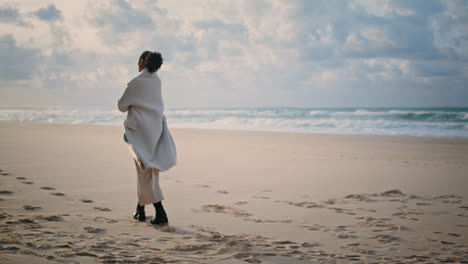 calm traveler walk beach on autumn weekend. lonely african american admiring