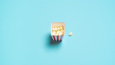 Stop-Motion-Video-Zum-Popcornessen.-Draufsicht-Einer-Popcornschachtel-Auf-Blauem-Hintergrund.