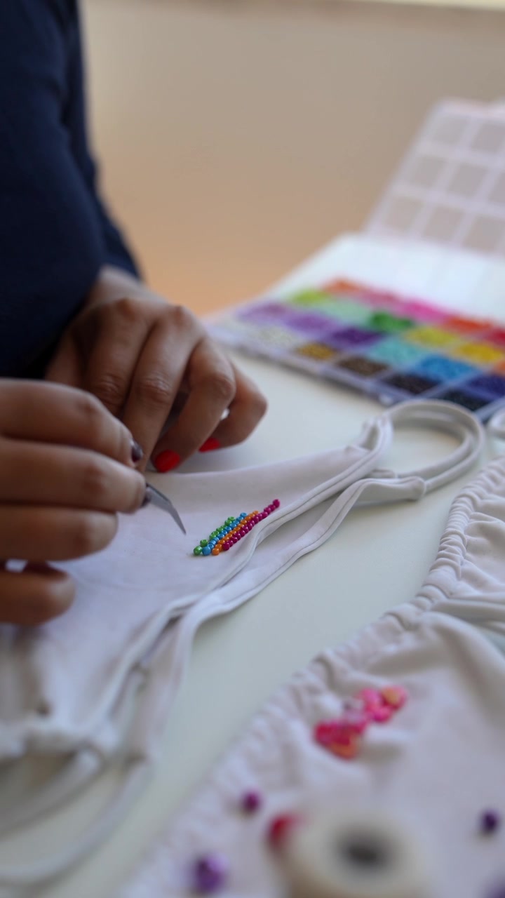 Artisan Decorating White Fabric with Colorful Beads Using Tweezers