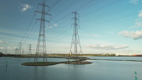 view across eling great marsh with high voltage transmission towers in southampton, england, uk - aerial drone shot