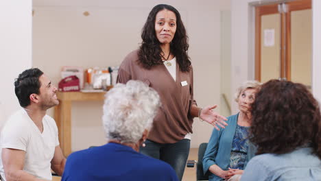 mature woman standing to address self help therapy group meeting in community center