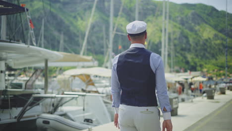 man walking in a harbor by the yachts