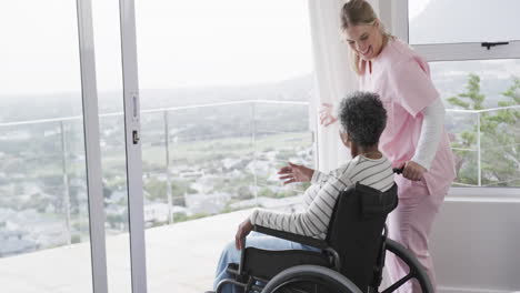 smiling caucasian nurse talking with senior african american woman patient, copy space, slow motion