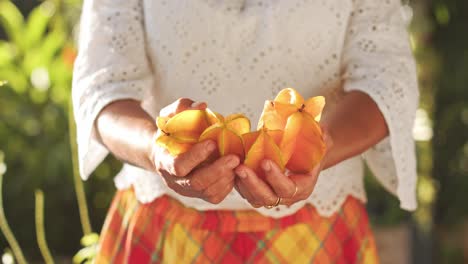 Woman-in-white-shirt-and-plaid-skirt-showing-starfruits-to-camera