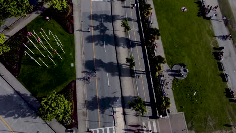 super smooth slow aerial dolly roll birds eye view over english bay park roads, bike lanes, bike rental booth palm trees canadian bc lgbtq pride flags sunny shadow crosswalk cones pilans covid-19