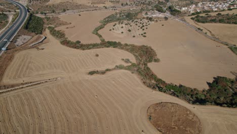 Aerial-drone-backward-moving-shot-over-agricultural-land-along-hilly-terrain-in-El-Torcal-de-Antequera,-Sierra,-Spain-at-daytime