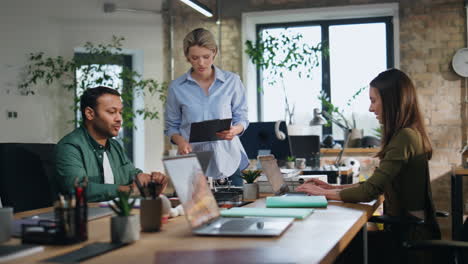 businesswoman supervising office workers in workplace. boss giving work task