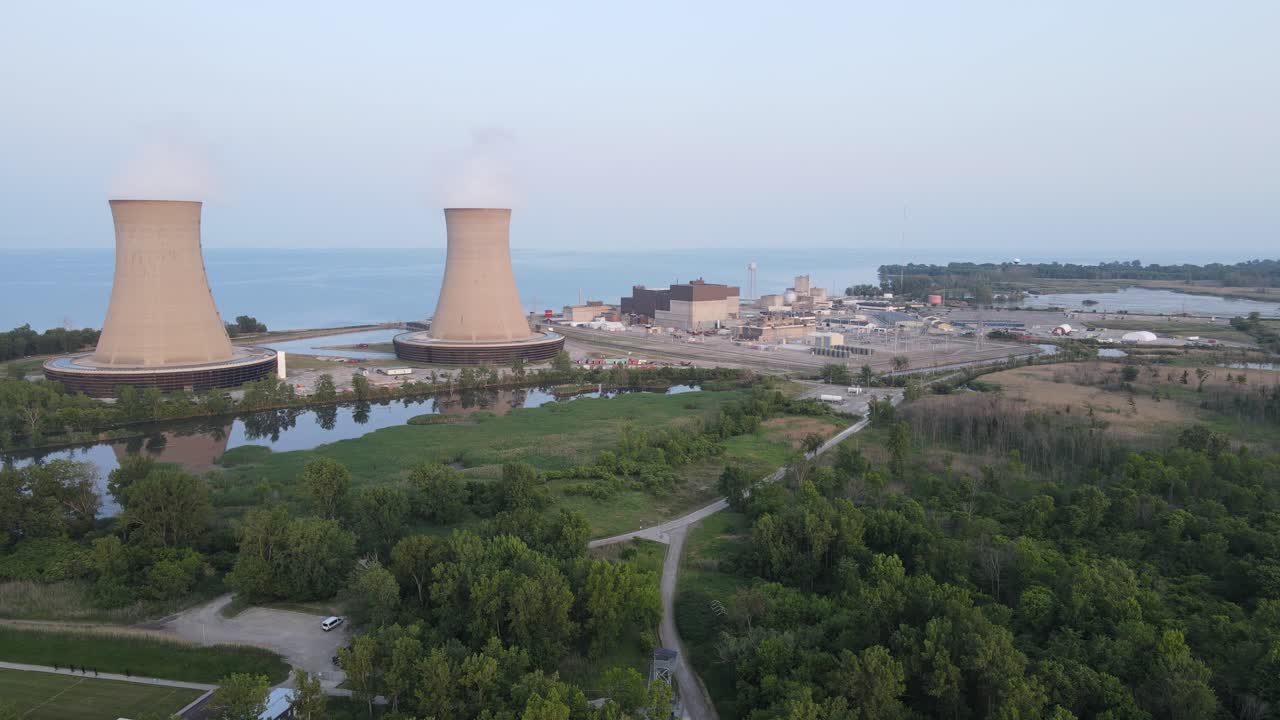 chimeneas de la planta de energía nuclear con humo ascendente en la costa del lago, vista aérea