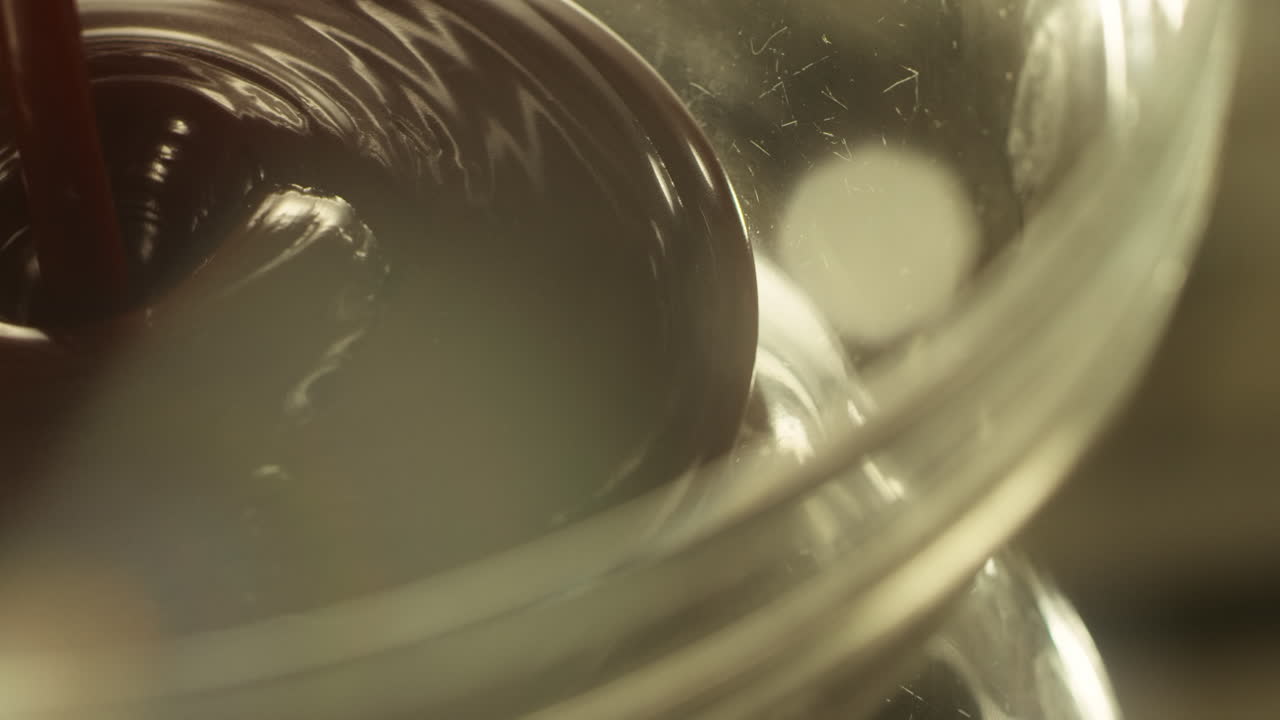 gotas líquidas de chocolate negro caliente goteando en un tazón de vidrio. jarabe de chocolate