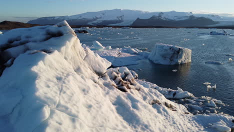 Revelación-De-Enormes-Icebergs-En-Un-Lago-Glaciar-Con-Pájaros-Volando-Cerca-De-La-Cámara