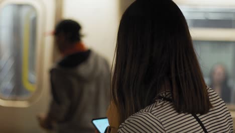 female in new york subway checking timetable with smartphone, slow motion close up