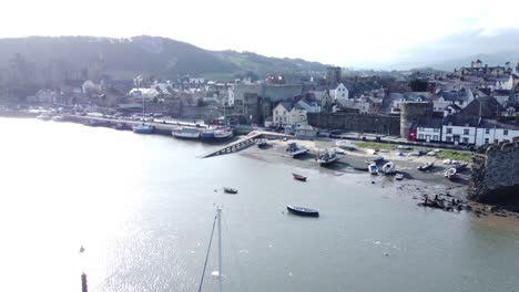 idyllic conwy castle and harbour fishing town coastal waterfront aerial slow rise over boats