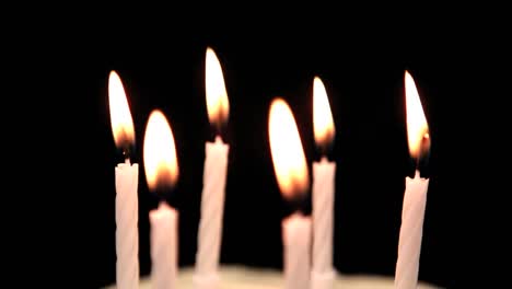 Animation-of-red-kaleidoscopic-shapes-moving-over-lit-birthday-cake-candles,-blown-out,-on-black
