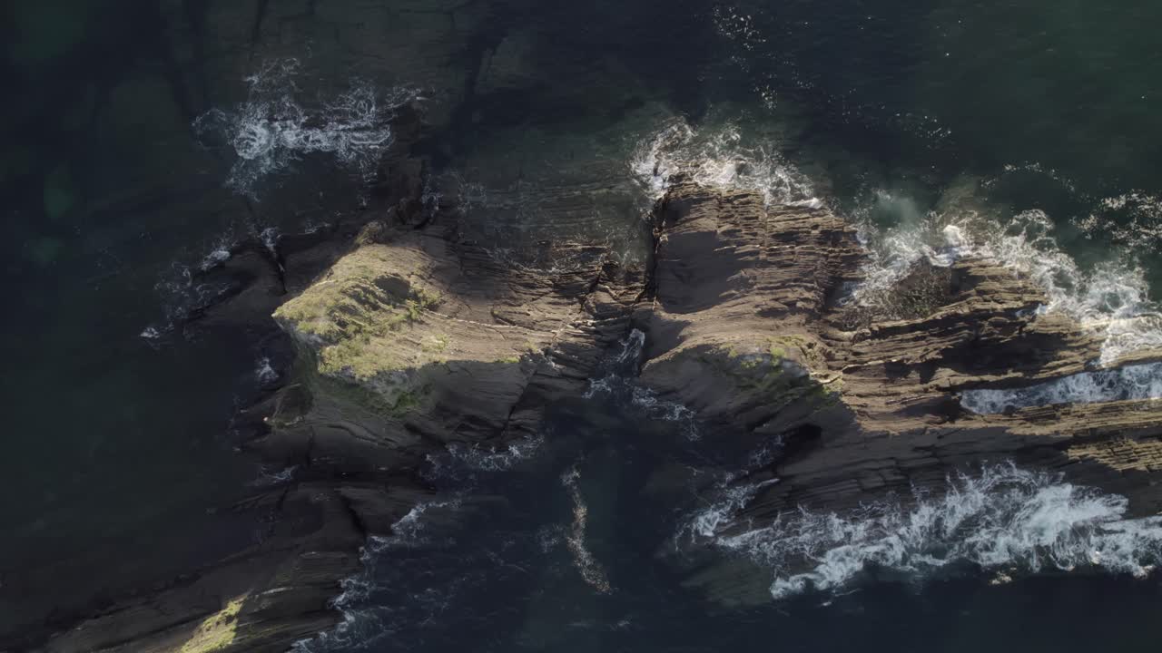 Riprese aeree di un'isola rocciosa con onde che si infrangono su di essa.