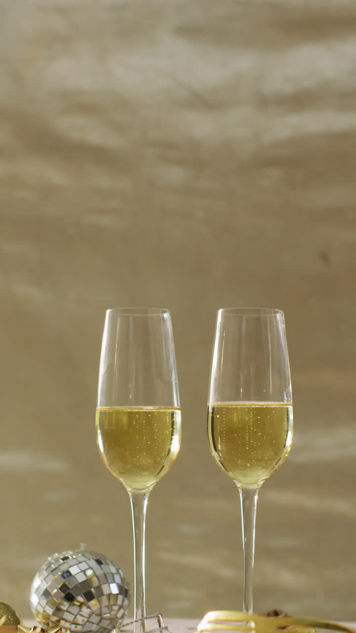 video vertical de dos vasos de champán, una mini pelota de discoteca y vasos de fiesta