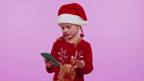 Girl-in-Christmas-sweater-using-credit-bank-card-smartphone-while-transferring-money-shopping-online