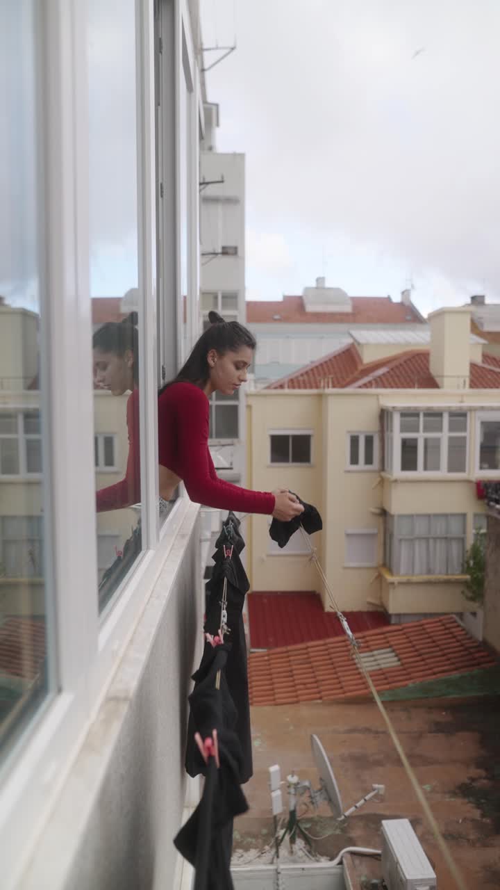 Woman hanging clothes on a balcony