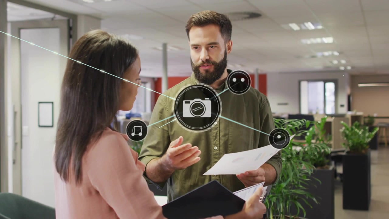 Due impiegati che esaminano documenti in un ufficio aziendale, icone di fotocamera o musica che appaiono e si espandono tra di loro.