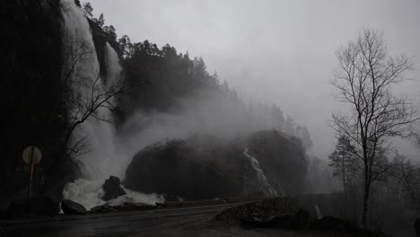vehicle passes along road 569 near hesjedalsfossen as rainstorm causes flooding. water spills toward road