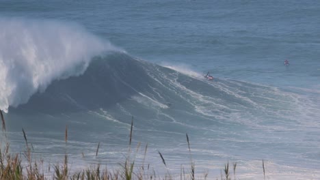 nazaré, portugal, toma de una moto acuática empujando a un surfista de olas grandes para montar una ola enorme en nazaré, portugal