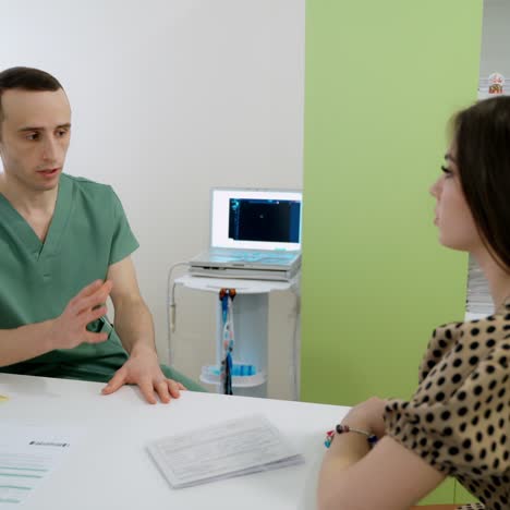 visit to a doctor. young male general practitioner in medical uniform consulting patient in office. young woman visiting doctor for regular checkup in clinic.