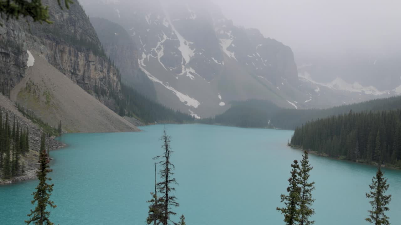 Crystal clear blue Moraine Lake in Banff National Park Alberta on a slightly foggy afternoon.