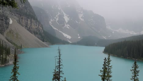 crystal clear blue moraine lake in banff national park alberta on a slightly foggy afternoon.