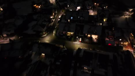 slow flight over american housing area with warm lights during snowy winter night. christmas decoration in windows along street. aerial top down flyover. homes in usa.