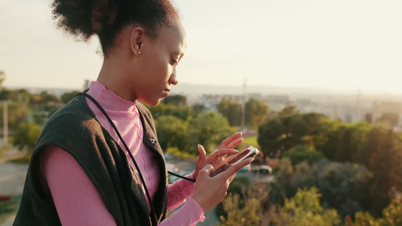 Mujer usando un smartphone en un parque urbano al atardecer