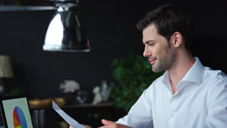 Businessman-analyzing-financial-reports-at-workplace.-Man-working-on-laptop