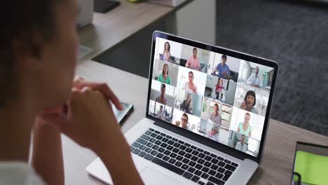 mujer afroamericana teniendo una videoconferencia en una computadora portátil con colegas de oficina en la oficina