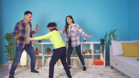 una familia feliz y linda jugando con los ojos vendados y divirtiéndose en casa.