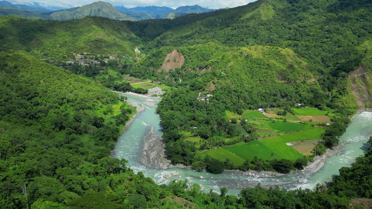 Slow gliding pan of the Chico River flowing through valleys between vibrant green trees and mountains in Bontoc, Nueva Vizcaya, Philippines, showcasing the landscape