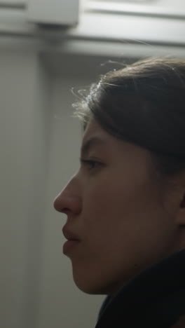 una toma de primer plano de una chica desconsolada con un abrigo marrón, mirando hacia arriba con una expresión sombría. la imagen captura su perfil mientras aparece profundamente en pensamiento, transmitiendo una sensación de tristeza