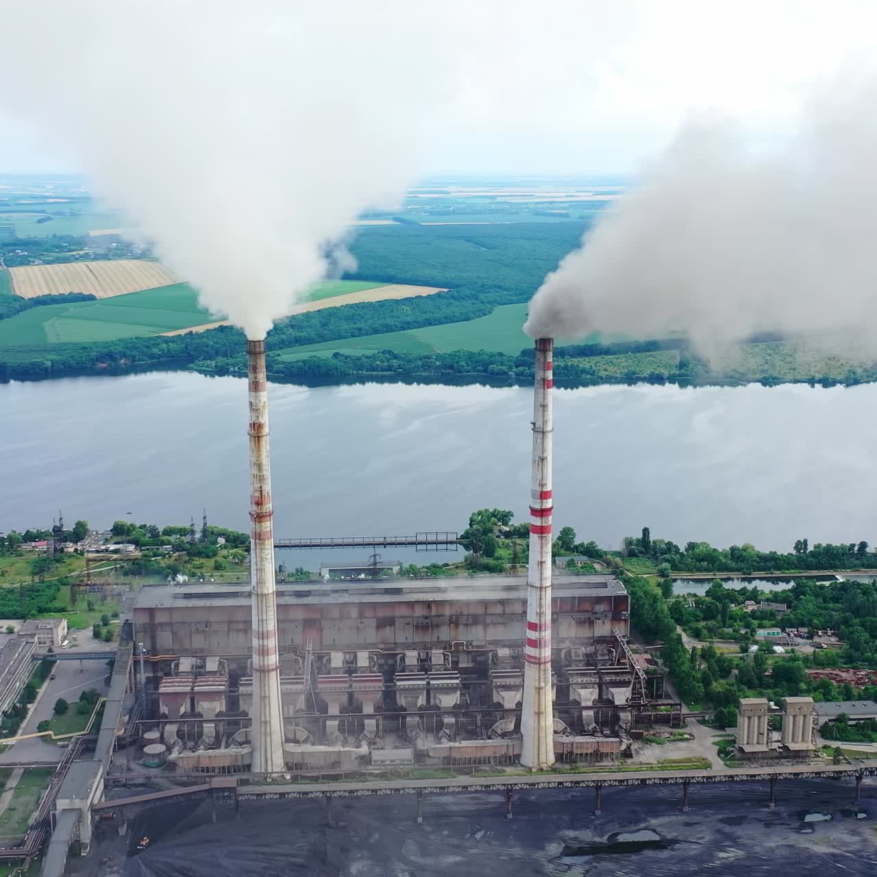 Harmful industry on river background. Factory pipes with smoke pouring into the atmosphere. Air pollution among beautiful nature