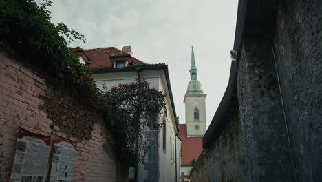 narrow alley with ivy walls and st. martin's cathedral tower bratislava slovakia