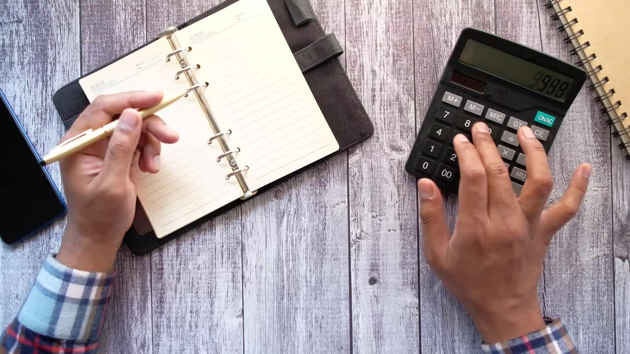 persona que trabaja en un escritorio con un cuaderno, una calculadora y un teléfono