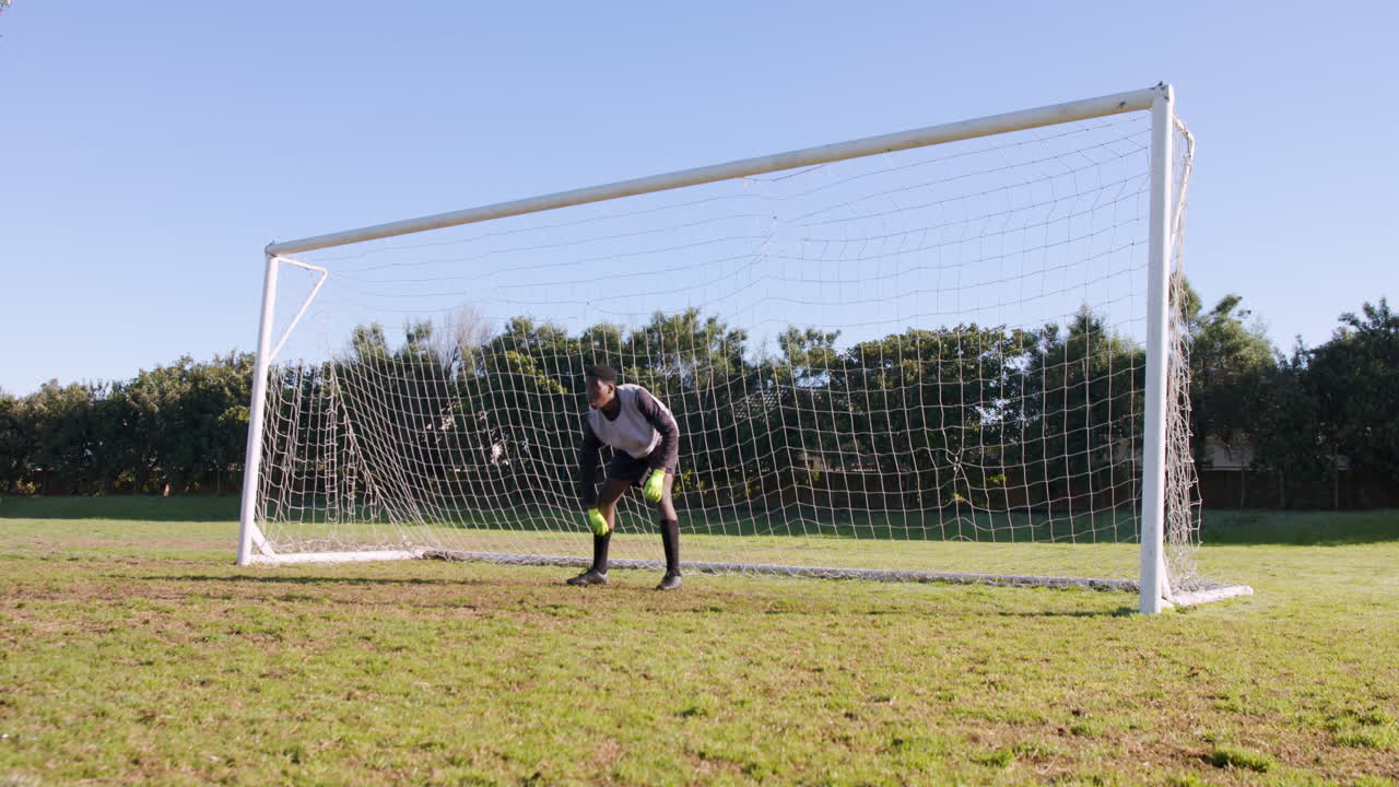 Goalkeeper in action, standing in front of soccer goal, ready to defend