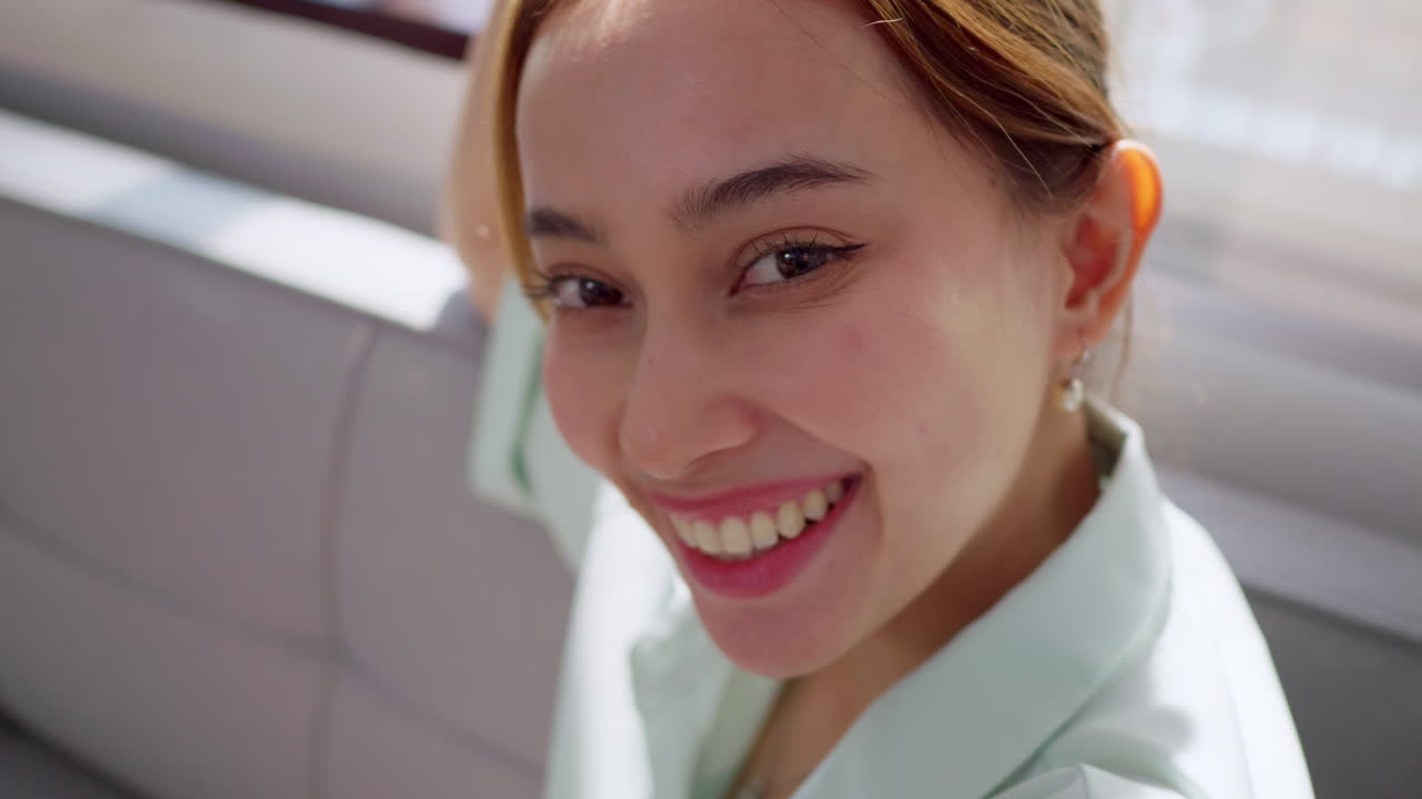 A young woman shares her happiness with a radiant smile in a sunny indoor setting.