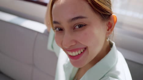 a young woman shares her happiness with a radiant smile in a sunny indoor setting.