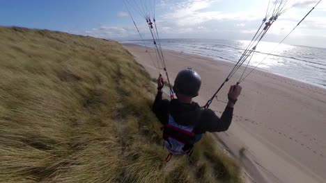 Paraglider-Flying-Close-To-Beach,-Extreme-Sports,-Coastal,-High-Speed-Speed-Soaring,-Beach-Sand,-Summer-Day,-Close-Up-Action-Cam,-Insta360,-Langevelderslag,-Netherlands