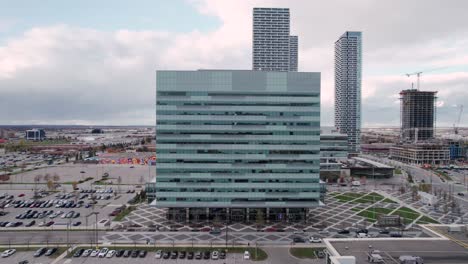 aerial view of modern high rise office building, plaza, parking lot, cars driving, construction. cloudy day