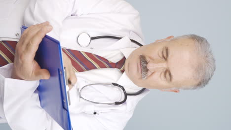 Vertical-video-of-The-old-doctor-examining-the-paperwork-is-thoughtful.