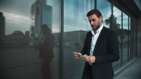 businessman-counting-money-on-city-street.Man-enjoying-dollar-banknotes-in-hands