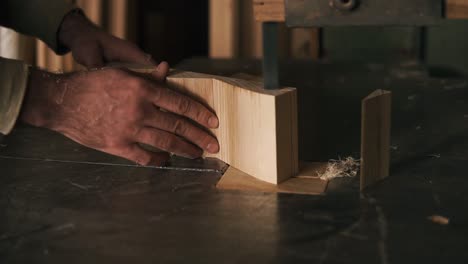 with the help of electric saws, the master's hands cuts off excess parts from the bar, making shape. sawdust fly from the machine. close up