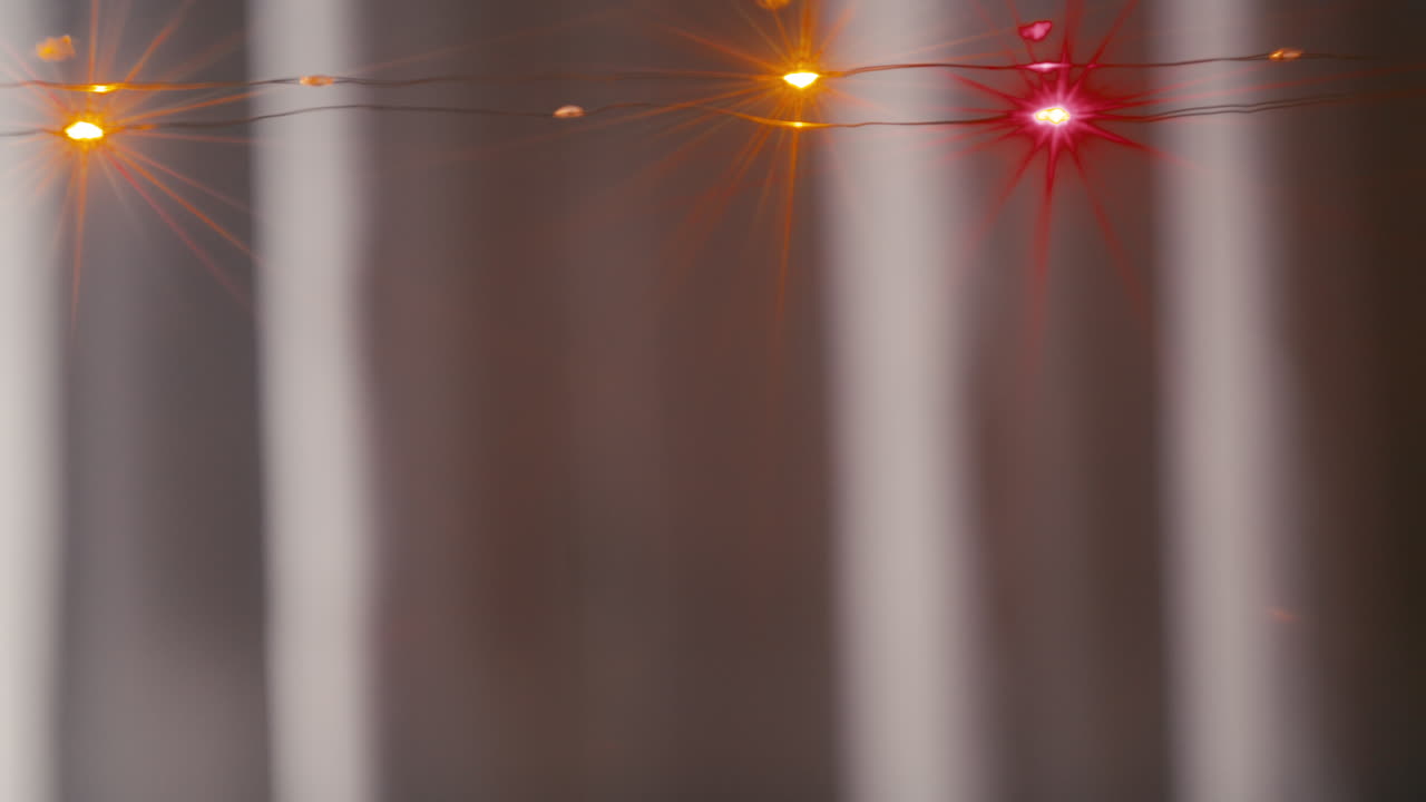 Flashing Christmas lights in front of a blue curtain background