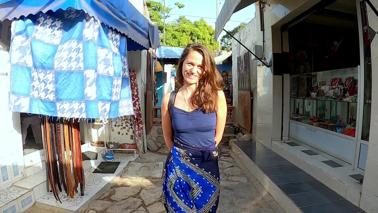 mujer europea sonriente caminando en el mercado en dakar, senegal