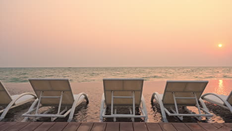 Empty-deck-chairs-on-seashore-with-sea-in-background-at-sunset