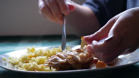 manos caucásicas de primer plano comiendo pollo y arroz